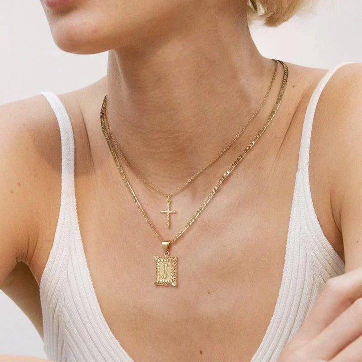 Woman in a white ribbed top wearing the layered cross necklace and square J pendant necklace 7