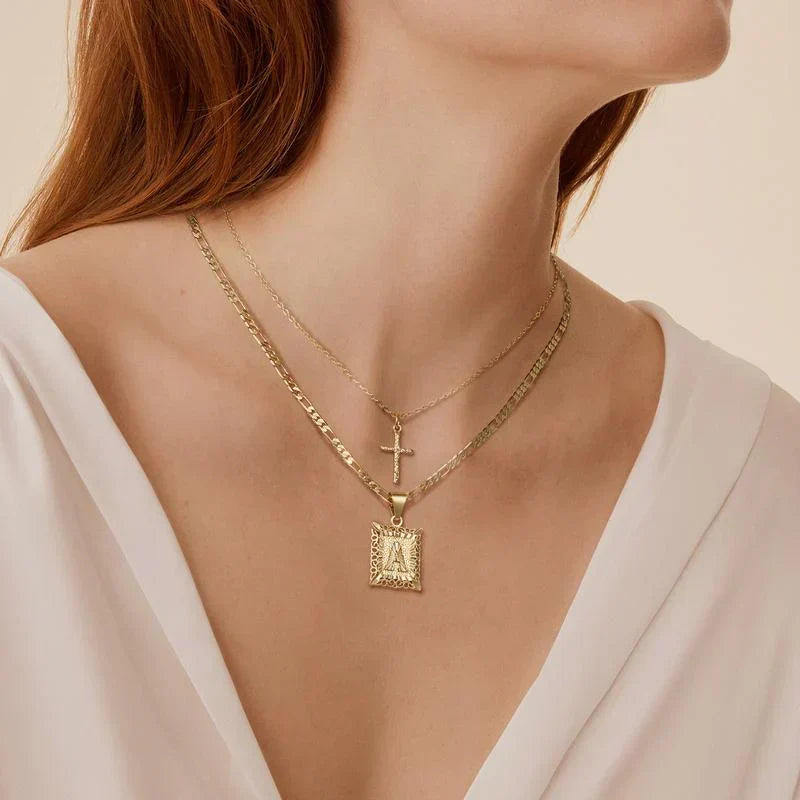 Woman with auburn hair in a white V-neck top wearing the layered cross and letter A necklaces 5