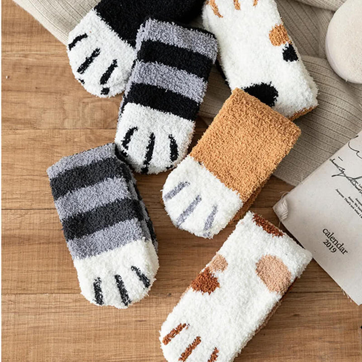 Flat lay of six fluffy socks on a wooden table, showing white toe pads with embroidered claw stripes 5