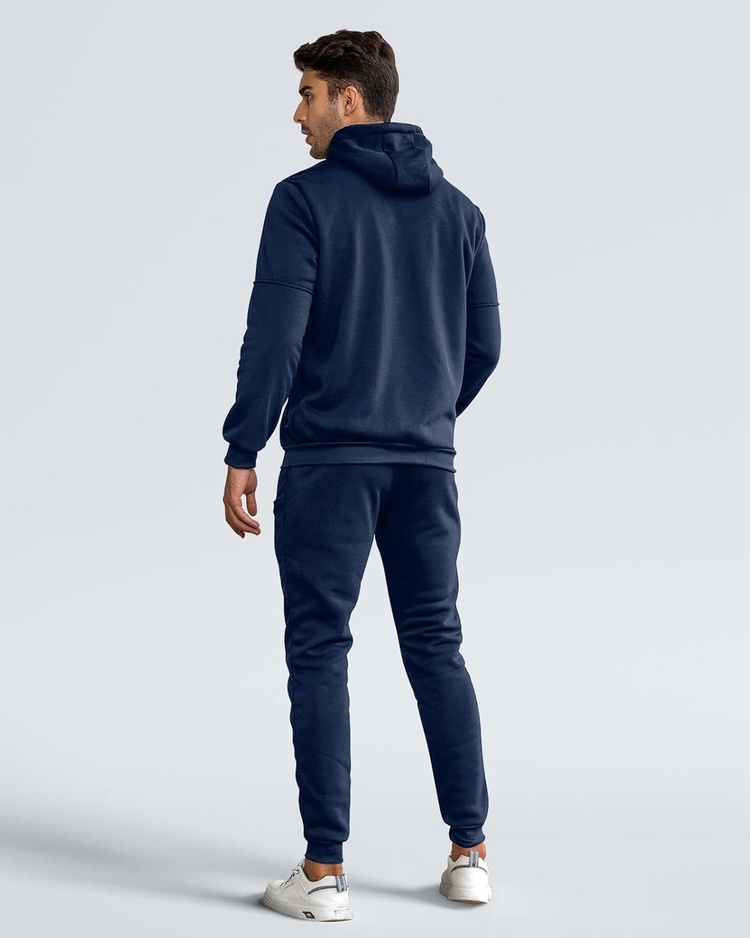 Back view of a man in a navy hoodie and matching joggers, looking over his shoulder 3