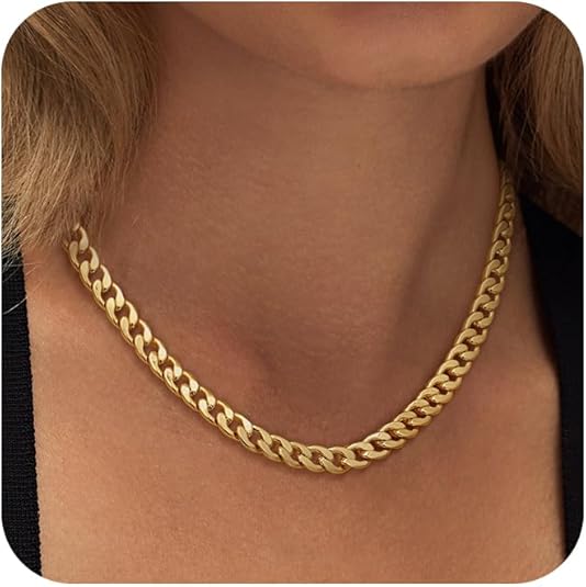 Close-up of a gold curb-link chain resting flat against a woman's collarbone, worn over a black top 1