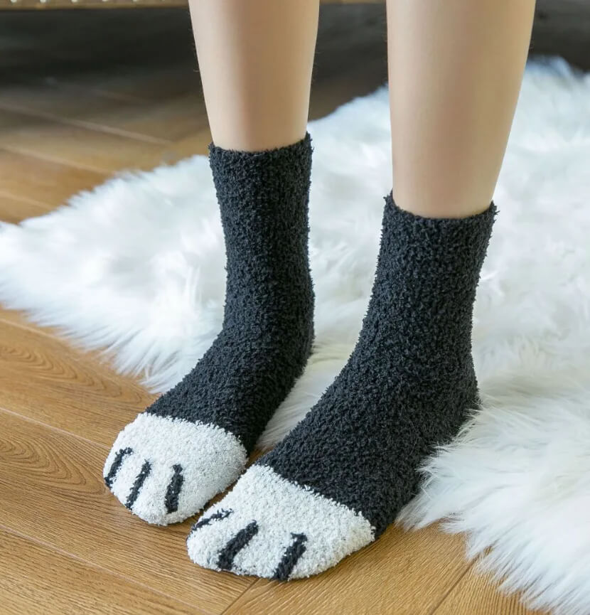 Model standing on a white fur rug in solid black fuzzy socks with white paw-pad toes 9