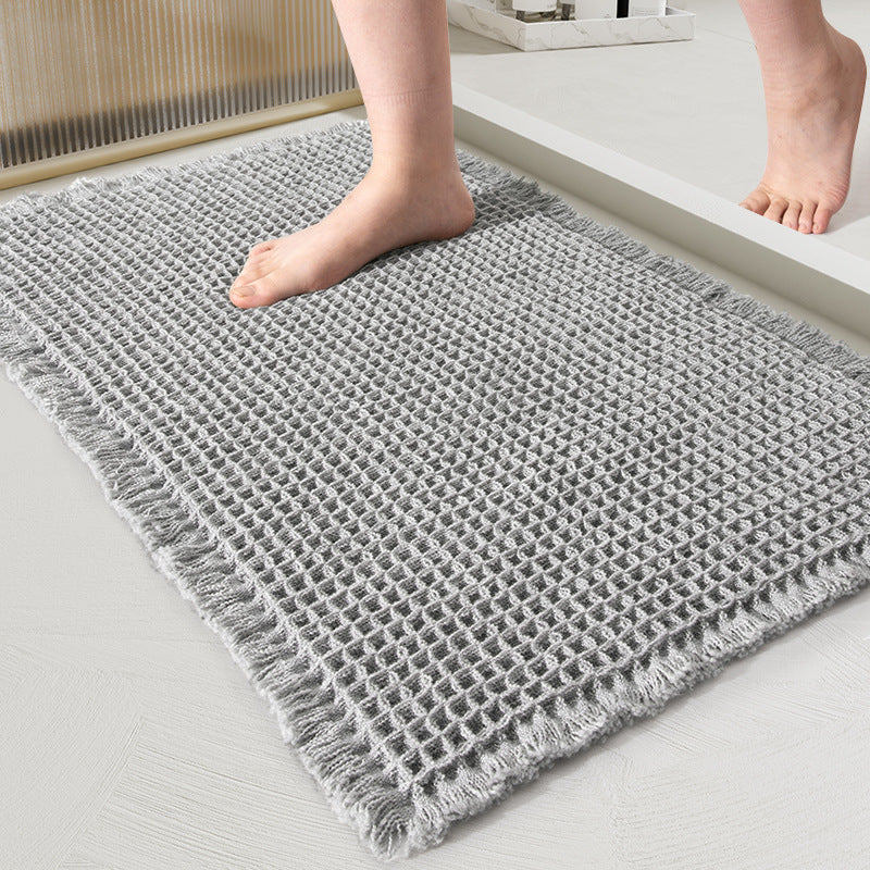 Close-up of the waffle-weave mat in light gray with fringed edges and a bare foot on it 10