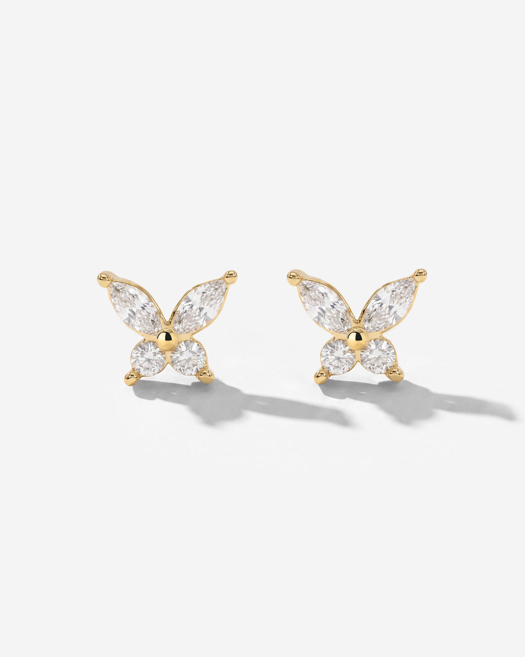 Pair of gold-tone butterfly studs with clear stones, seen from the front on a white surface 2