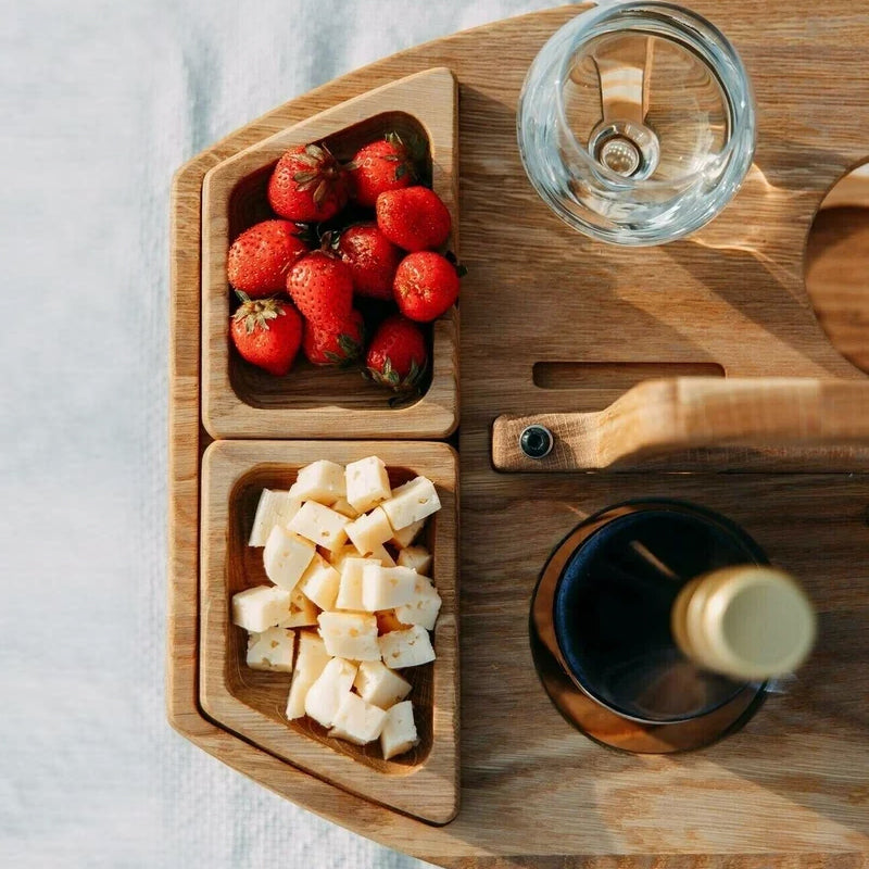 Close-up from above of two wooden snack trays filled with strawberries and cubed cheese, next to a wine glass and bottle 9