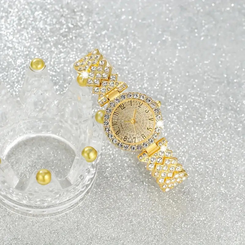 Gold crystal watch resting against a clear crown-shaped display holder with gold beads on glittery silver 3