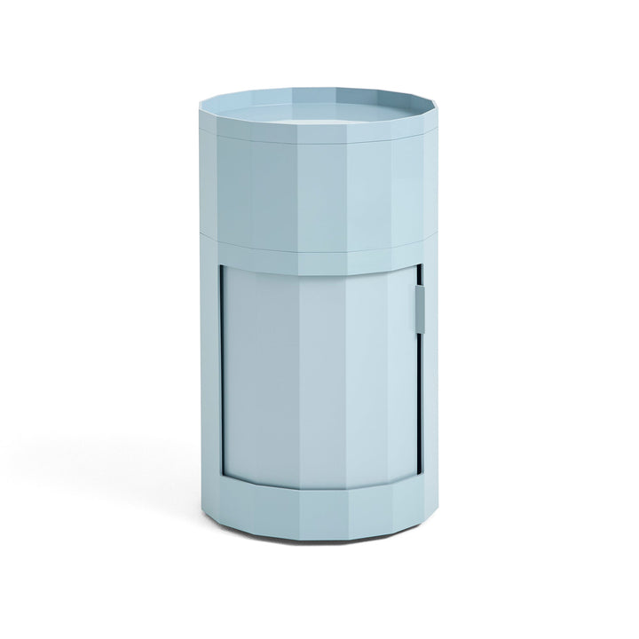Tall round cabinet in light blue with faceted sides, raised tray top and closed door 3
