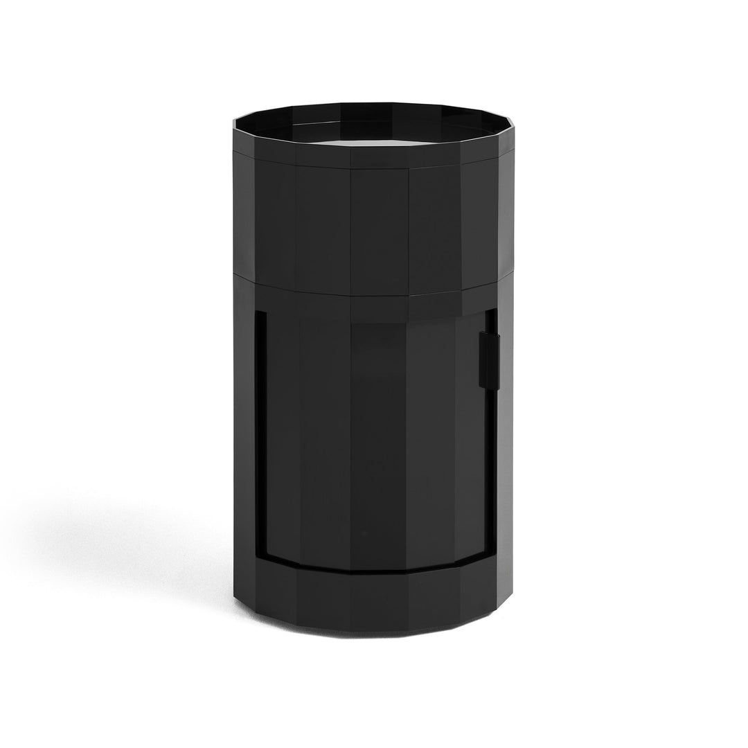 Tall round cabinet in glossy black with faceted sides, tray top and closed door on white background 4