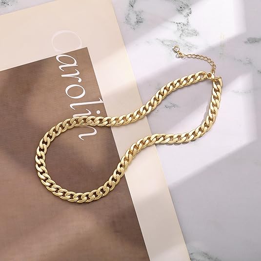 Gold chain laid flat on a marble and beige card, showing the extender chain and clasp 4