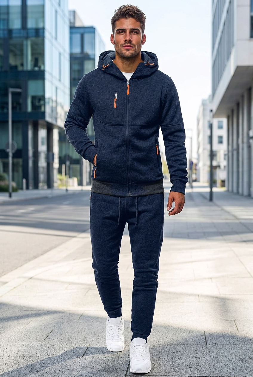 Man walking down a city street in a navy zip hoodie and joggers with orange zipper pulls 1