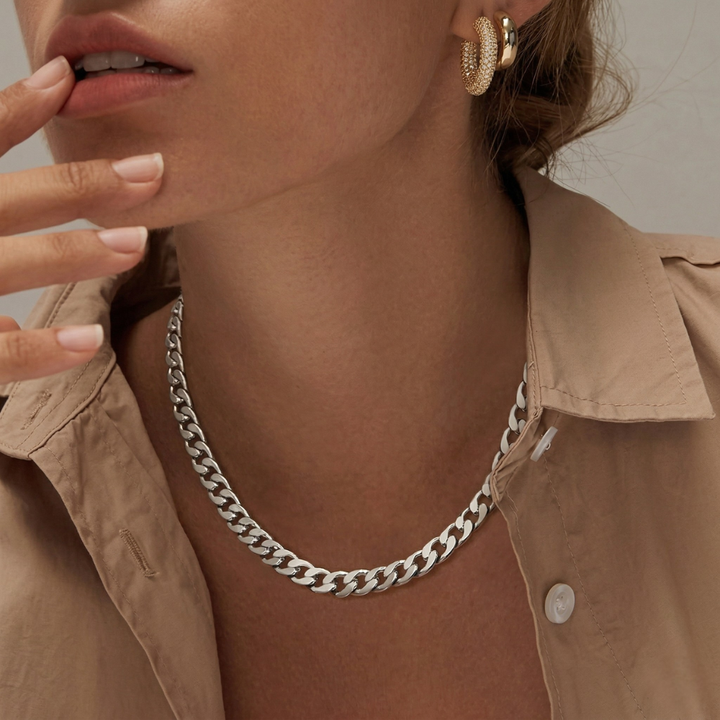 Silver-tone chain worn with a beige shirt and gold hoop earrings, model's fingers touching her lips 7