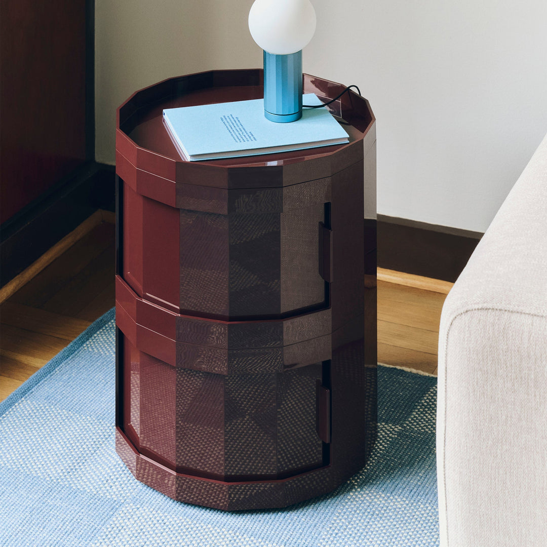 Burgundy two-door cabinet used as a side table by a sofa, holding a book and blue lamp 29