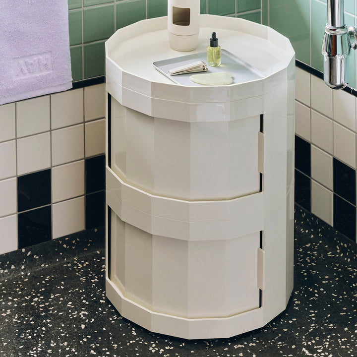 Two-tier cream cabinet in a tiled bathroom with skincare items on its rimmed top 51