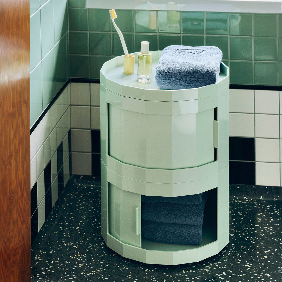 Mint green cabinet in a tiled bathroom, lower door open showing towels, toiletries on top 35