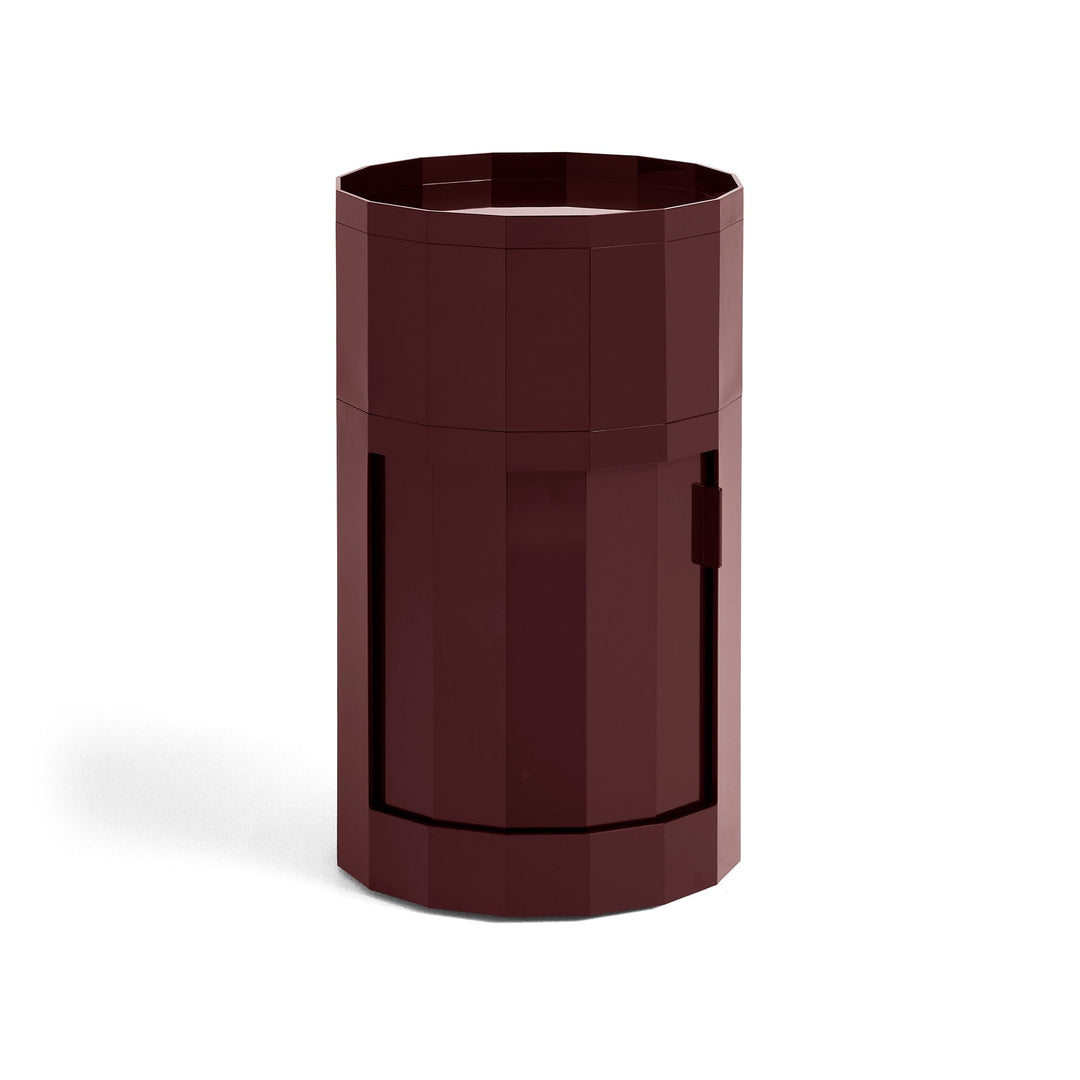 Tall round cabinet in deep burgundy with faceted sides, tray top and closed door 19