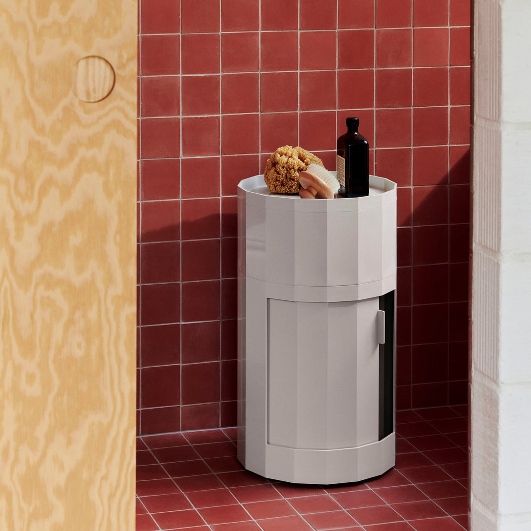 Light gray round cabinet with open door in a red-tiled bathroom, holding a sponge, brush and bottle on top 1