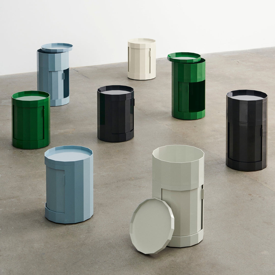 Several cabinets in blue, green, black and cream arranged on a concrete floor, some with lids lifted 46