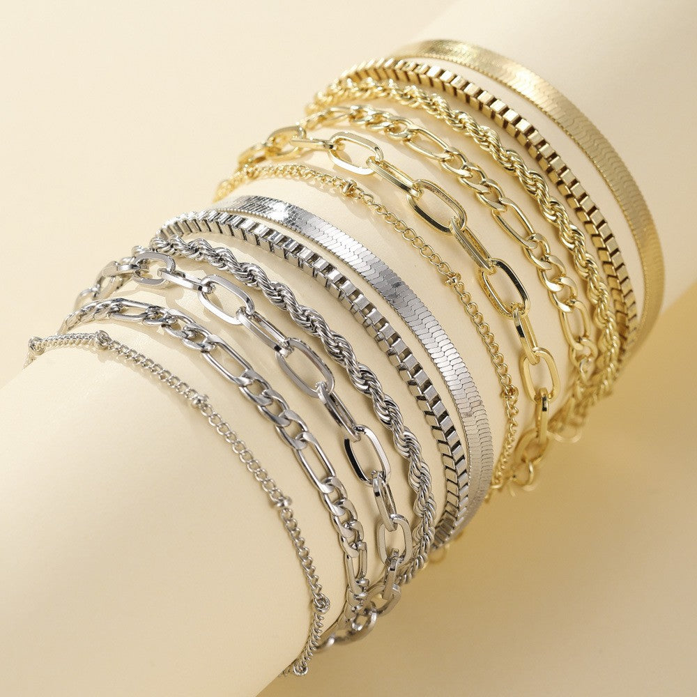 Flat lay of ten chain bracelets in gold and silver tones on a cream cylinder 1