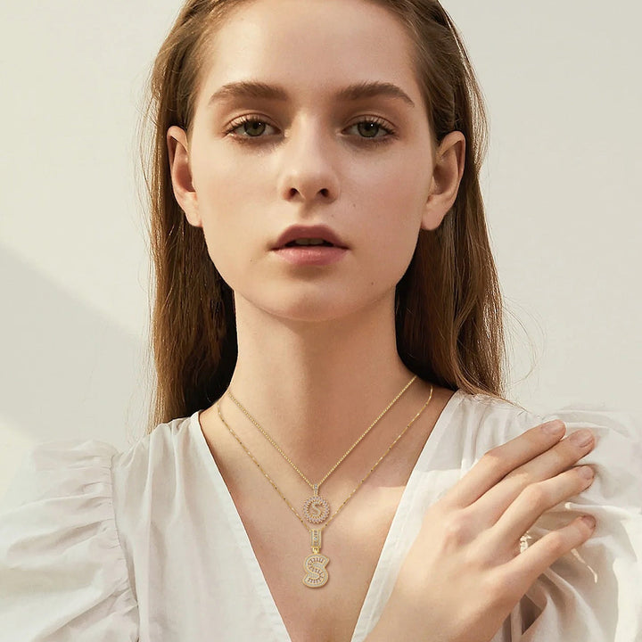 Woman in a white puff-sleeve blouse wearing the two gold initial pendants, one hand resting on her shoulder 4
