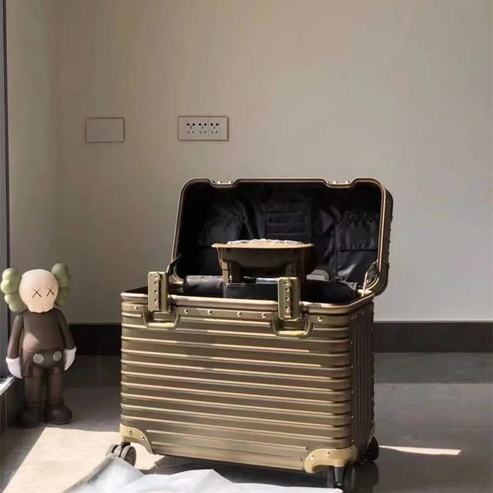 Gold-toned suitcase opened to show the dark lined interior and pockets, with a figurine nearby 9