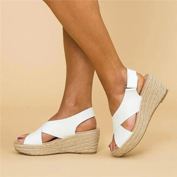 White crisscross-strap espadrille wedges with ankle straps, shown on a model against a beige backdrop 5