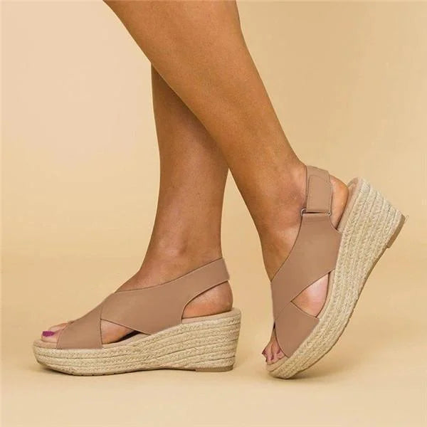 Tan crisscross-strap espadrille wedges with an ankle strap, worn on a plain beige backdrop 2