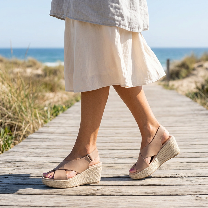 Woman walking on a beach boardwalk in tan crisscross wedge sandals with a linen skirt 1
