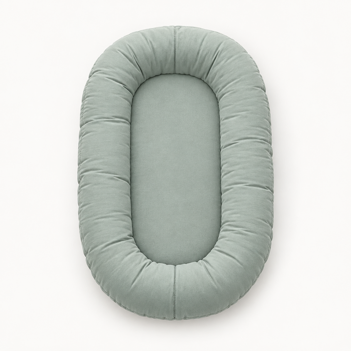 Empty sage-green oval lounger with a raised padded rim, seen from above on white 8