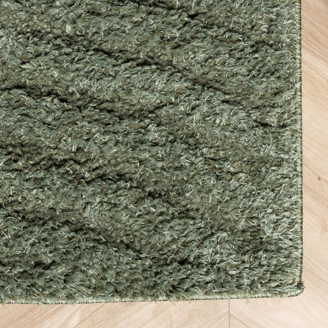 Rug corner close-up showing the stitched edge and dense pile against light herringbone flooring 5