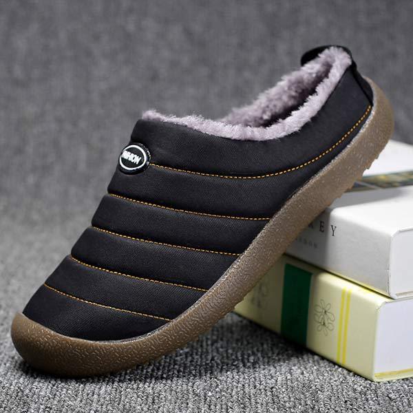 Single black quilted slipper tilted against books, showing the side profile and thick brown sole 10