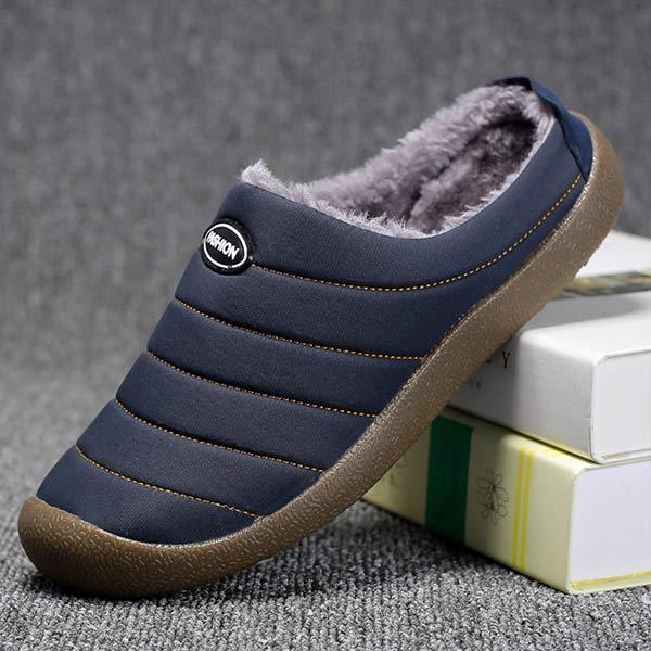 Single navy blue quilted slipper leaning on books, showing the fleece interior and side stitching 7