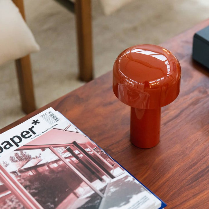 Glossy red-orange lamp seen from above on a wooden coffee table beside a magazine 14