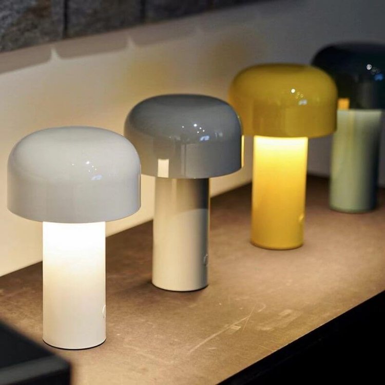 Row of lit lamps in white, gray, yellow and dark teal on a shelf along a wall 19