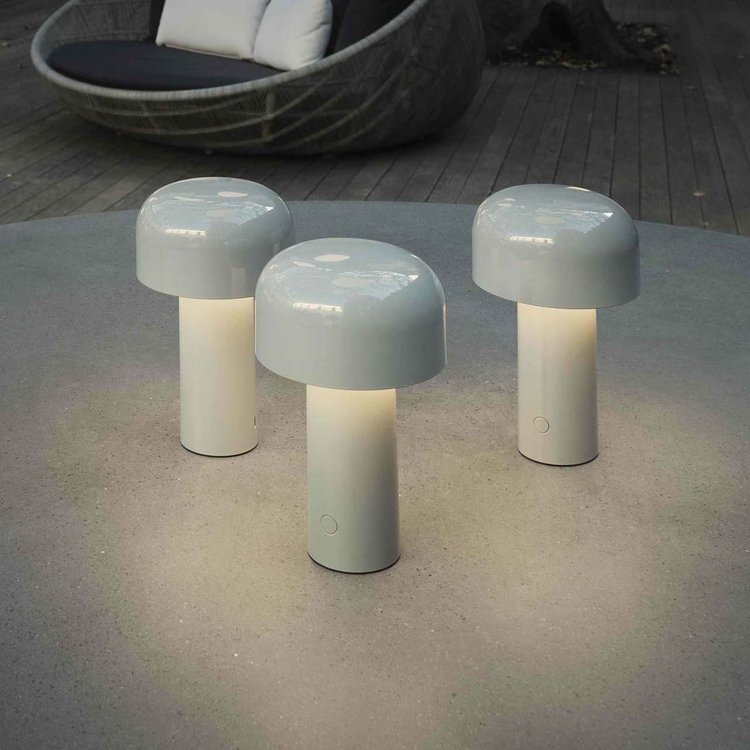Three light gray lamps glowing on an outdoor concrete table, with a woven lounge chair behind 7