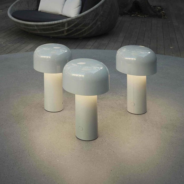 Three light gray lamps glowing warmly on a round outdoor table near a wicker lounger 7