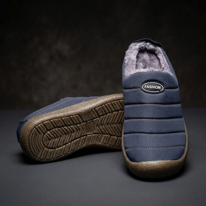 Navy blue quilted slippers, one standing upright to show the front and one tilted to reveal the tread sole 18