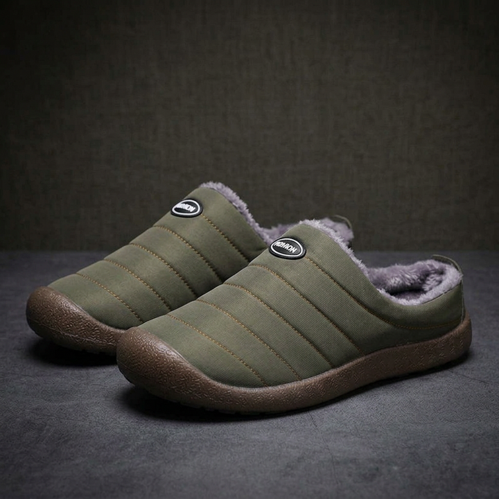 Pair of olive green quilted slippers with gray fleece lining on a dark gray surface 17