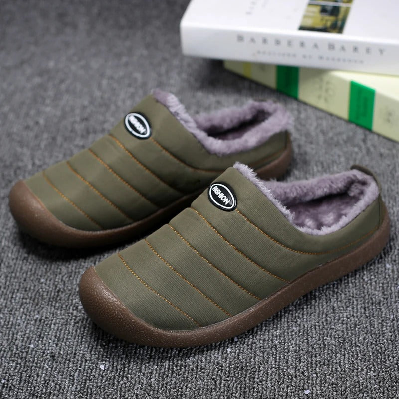 Pair of olive green quilted slippers with gray fleece lining on a gray carpet beside books 2