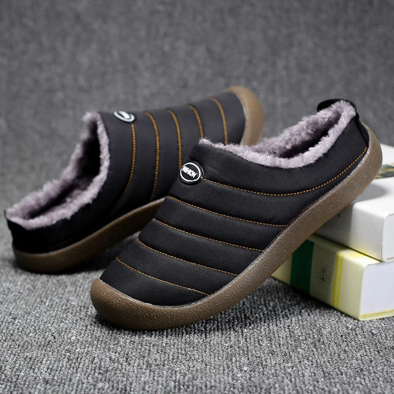 Black quilted slippers with orange stitching and plush lining, one slipper angled to show the inside 9