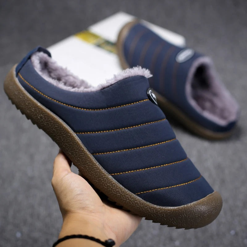Hand holding a navy blue quilted slipper to show the stitched ridges and thick brown sole 6