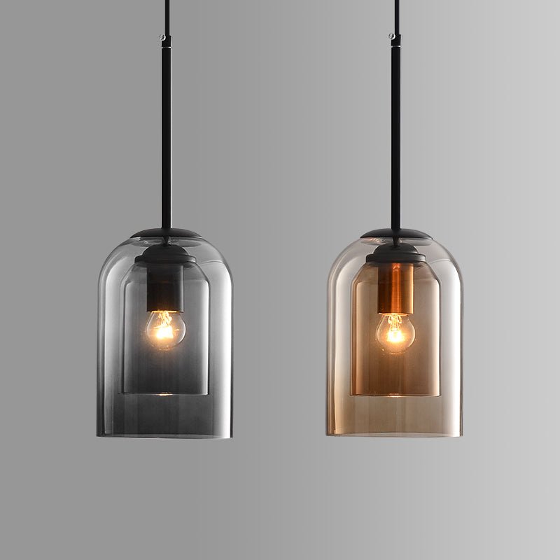 Two double-layered glass pendant lights side by side, one in smoky gray and one in amber, each lit 2