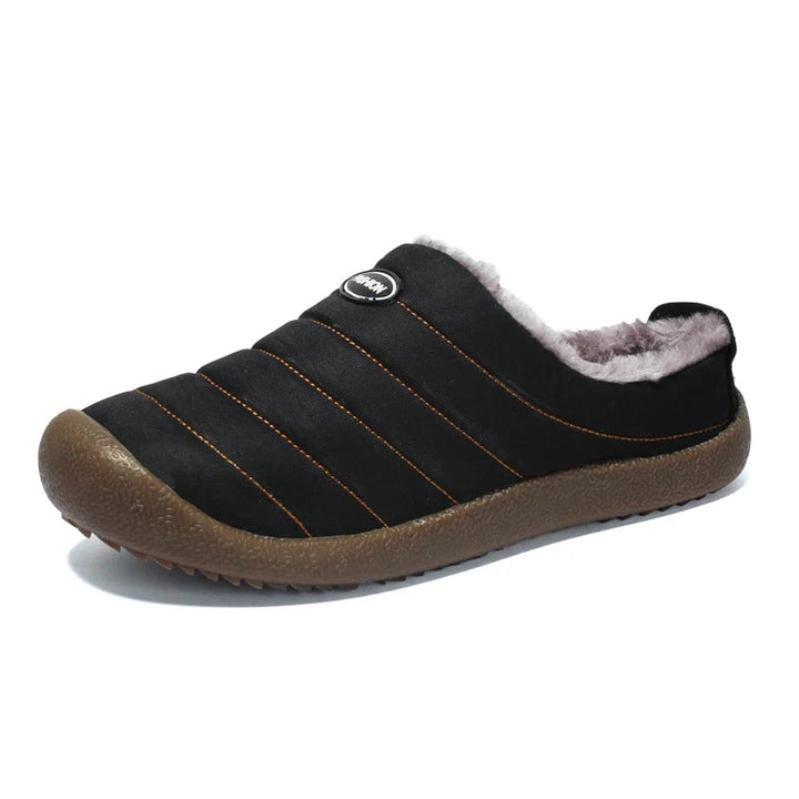 Single black quilted slipper with fleece lining and brown sole, angled view on a white background 16