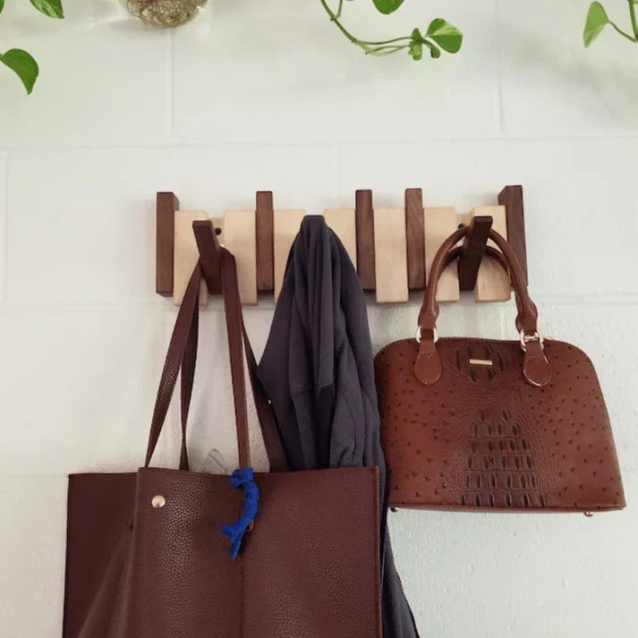 Two-tone wooden rack on a white brick wall, hung with brown leather totes and a gray jacket 3