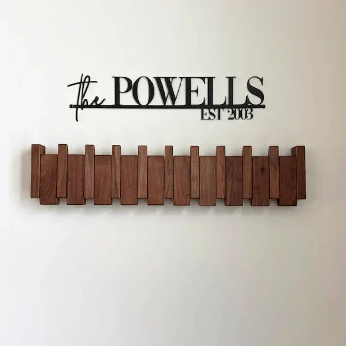 Dark wood rack with all hooks folded flat, mounted below a black personalized name sign 5